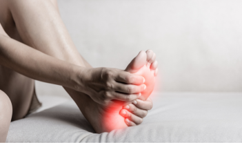 Person holding their foot with highlighted arch pain, representing flat feet condition and how custom orthotics can help alleviate discomfort and improve mobility.